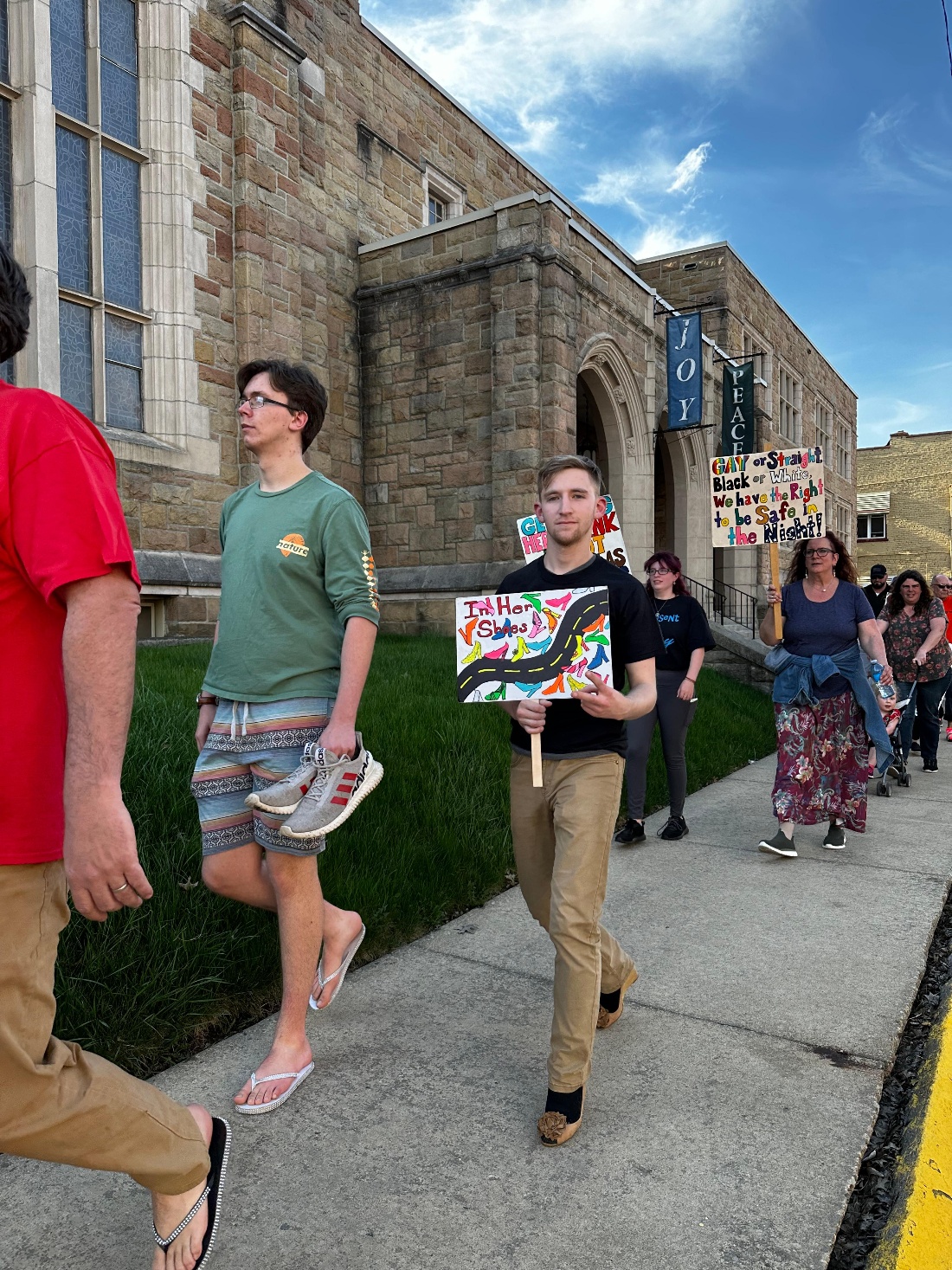 People walk and hold signs during YWCA Bradford's Walk a Mile in Her Shoes event. The event benefited the Victim's Resource Center